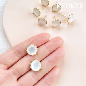 Puede incluir: Un conjunto de ocho hallazgos de pendientes de tono dorado con cabujones de vidrio blanco. Los hallazgos tienen un bucle en la parte posterior para sujetar a una cadena u otras joyas.