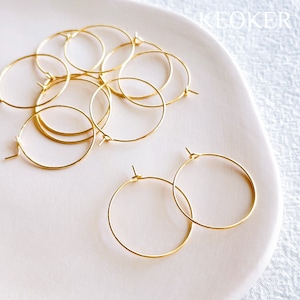 May include: A set of gold hoop earrings. The earrings are small and delicate, and they are perfect for everyday wear.