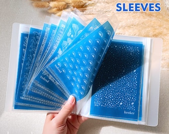 May include: A clear plastic binder with 40 blue plastic sleeves. Each sleeve has a different white design. The binder has the word "keoker" printed on the front and back. The text "40 PSC SLEEVES" is printed on the top right corner of the binder.