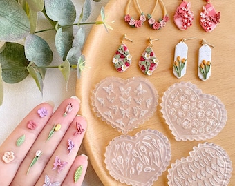 May include: Four heart-shaped silicone molds for making polymer clay earrings. The molds feature different designs: butterflies, flowers, tulips, and leaves. There are also six pairs of polymer clay earrings with floral designs.