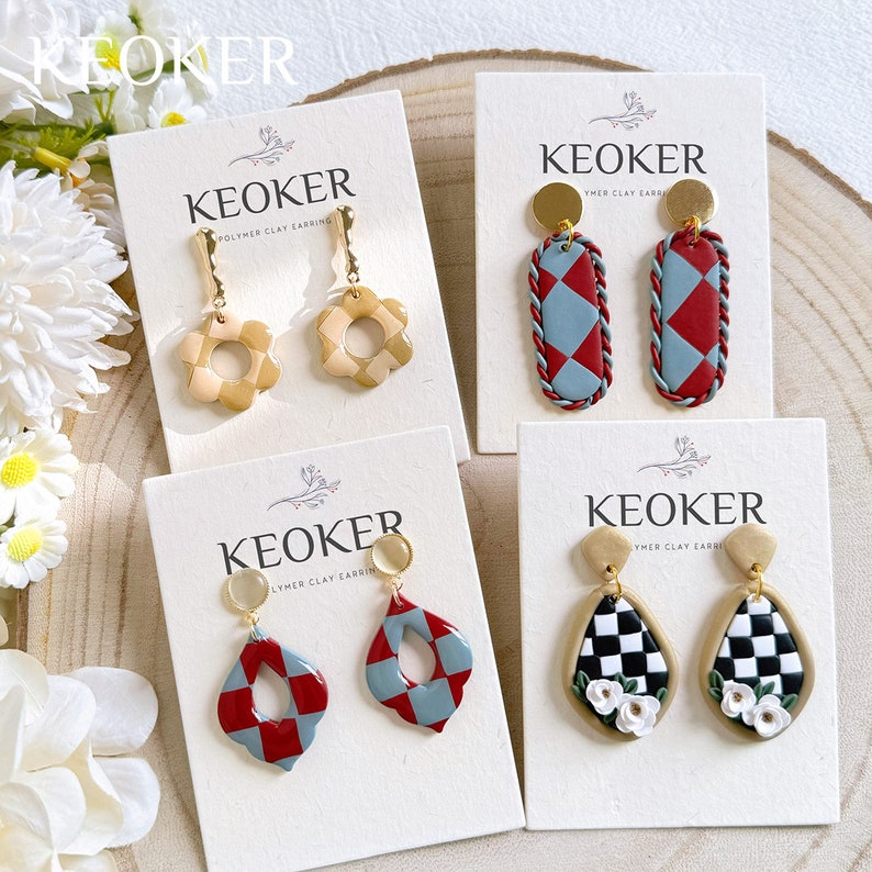 Pu&ograve; includere: Quattro paia di orecchini in argilla polimerica su carte bianche con il nome del marchio "KEOKER" stampato su ogni carta. Gli orecchini presentano diversi motivi geometrici in rosso, blu, bianco e beige.