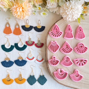 Peut inclure: Un ensemble de 12 moules à boucles d'oreilles en argile polymère rose de différentes formes en éventail. Les moules sont présentés sur une surface en bois avec une variété de boucles d'oreilles en argile polymère faites à la main dans différentes couleurs et designs.