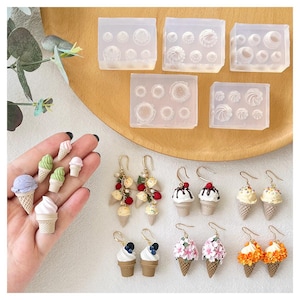 Pode incluir: Uma coleção de berloques e brincos em miniatura em forma de cones de sorvete com várias coberturas como frutas, flores e calda de chocolate, junto com cinco moldes de silicone transparente com formas para criar pequenos acessórios.