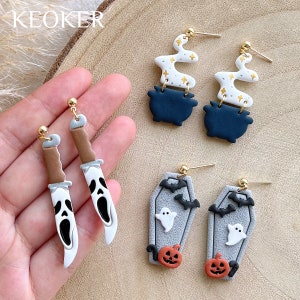 May include: Halloween-themed earrings in various designs. Includes earrings shaped like a knife with a ghost face, a cauldron with smoke, and a coffin with a ghost, bats, and a jack-o'-lantern. Gold-colored earring posts.