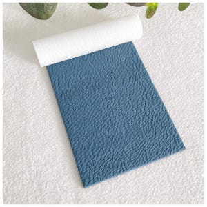 May include: A sheet of blue faux leather with a textured surface. The leather is rolled up and has a white backing.