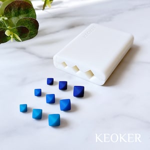 May include: A white silicone mould with four pyramid-shaped cavities.  The mould is labelled "KEOKER".  There are nine blue and teal pyramid-shaped resin pieces scattered around the mould.