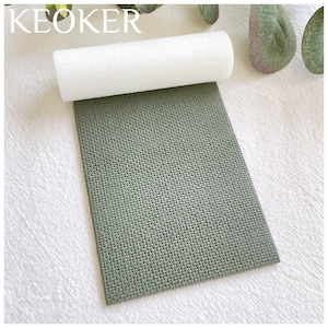 May include: A green textured silicone mat with a white rolling pin on top. The mat is designed to be used for rolling out fondant or other types of dough.