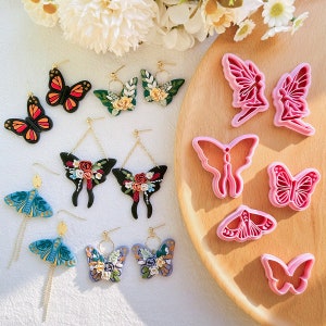 Könnte beinhalten: Sortiment handgefertigter Ohrringe aus Polymer Clay mit Schmetterlings- und Blumenmotiven. Die Ohrringe werden auf einer Holzoberfläche mit verschiedenen Ausstechern in Form von Schmetterlingen präsentiert.