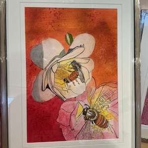 May include: Watercolor painting of two bees on flowers, framed in a silver metal frame. The flowers are white and pink, with yellow centers. The background is a gradient of orange and red. The bees are brown and black with yellow stripes.