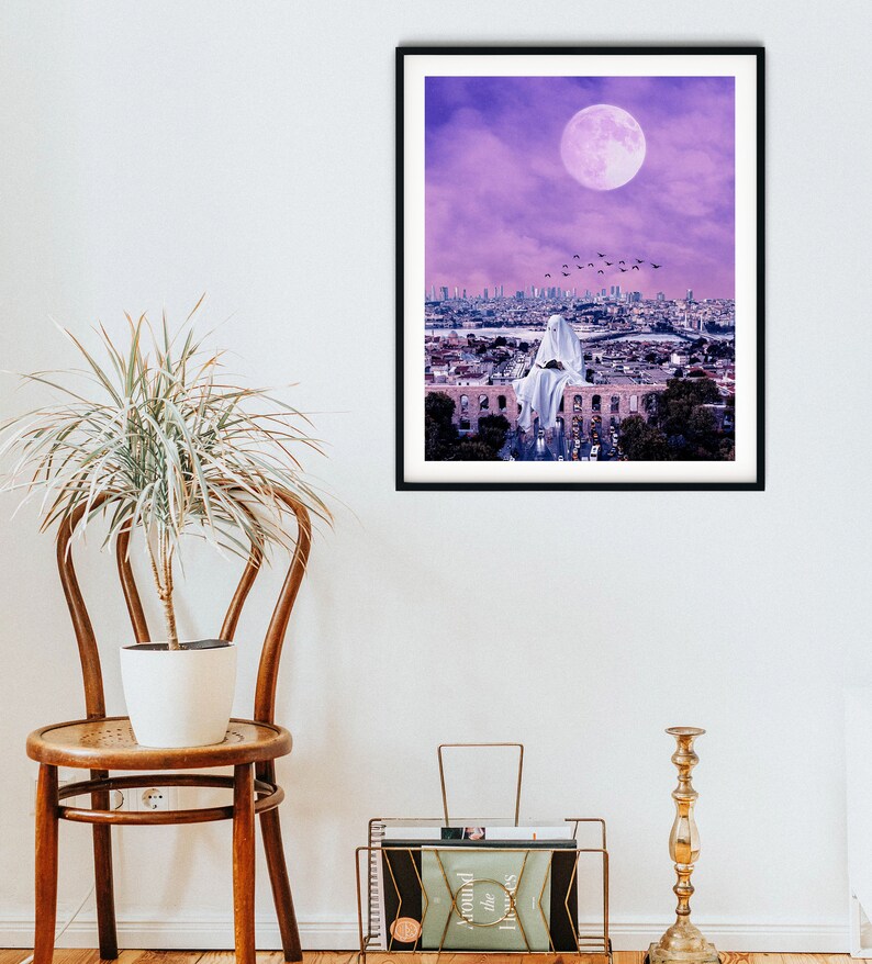 May include: A digital art print featuring a white ghost figure sitting on a rooftop overlooking a city skyline. The sky is a vibrant purple with a large, full moon.