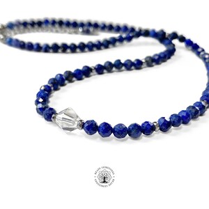 May include: A blue lapis lazuli beaded necklace with a clear crystal bead accent. The necklace is made with faceted beads and has a silver clasp.