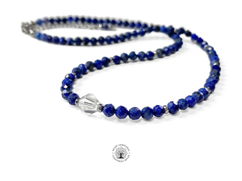 May include: A blue lapis lazuli beaded necklace with a clear crystal bead accent. The necklace is made with faceted beads and has a silver clasp.