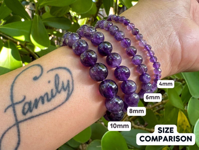 May include: Four amethyst bracelets of different sizes, 4mm, 6mm, 8mm, and 10mm, are shown on a person's wrist. The bracelets are stacked on top of each other, with the smallest bracelet on top and the largest bracelet on the bottom. The text "SIZE COMPARISON" is visible below the bracelets.