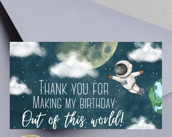Peut inclure: Une étiquette de sac cadeau bleue et blanche avec un astronaute flottant dans l'espace avec une lune et des étoiles en arrière-plan. Le texte dit "Merci d'avoir fait de mon anniversaire un moment extraordinaire !" et "Designed Rai's Way". L'étiquette mesure 8,9 cm sur 5,1 cm.