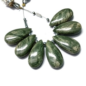 May include: A strand of green and white gemstone beads in a teardrop shape. The beads are strung on a silver wire with silver spacers.