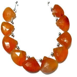 Könnte beinhalten: Eine Kette aus orangefarbenen Karneol-Edelsteinen, jede Perle ist facettiert und tropfenförmig. Die Perlen sind auf einem Silberdraht aufgefädelt, mit silbernen Zwischenperlen zwischen jeder Karneolperle.