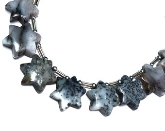 May include: A necklace made of silver and grey star-shaped beads. The beads are made of a mottled grey and white stone.