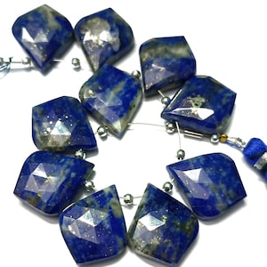 May include: A strand of faceted lapis lazuli gemstone beads with gold flecks. The beads are a deep blue color and have a faceted, diamond-like shape.