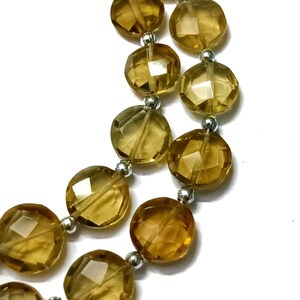 May include: A strand of golden brown faceted gemstone beads with silver spacers. The beads are round and have a smooth, polished finish.