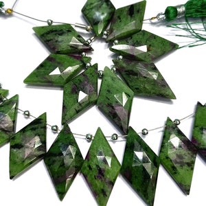 May include: A strand of green and black gemstone beads with a faceted diamond shape. The beads are strung on a silver wire with silver spacer beads.