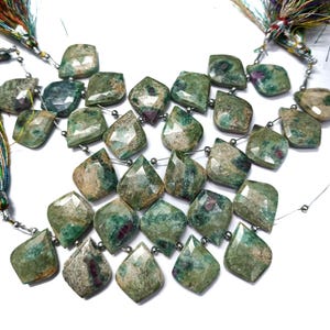 May include: A strand of green and brown gemstone beads with a faceted, teardrop shape. The beads are strung on silver wire with silver spacers between each bead.