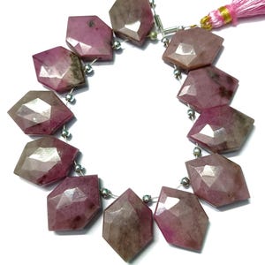 May include: A strand of pink and grey gemstone beads with a faceted, geometric shape. The beads are strung on a silver wire with silver spacers. A pink tassel hangs from the end of the strand.
