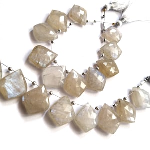 May include: Strands of faceted, light-colored gemstone beads. The beads are a mix of pale beige and translucent, with a geometric, diamond-like shape. Each bead is strung on a thin, silver-colored wire, with small silver beads separating them.