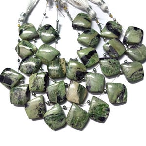 May include: A strand of green and black gemstone beads with a faceted, square shape. The beads are strung on a silver wire with silver spacer beads.