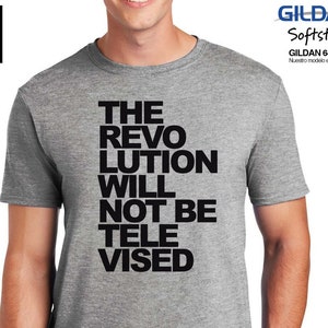 May include: A heather grey t-shirt with black text that reads "THE REVOLUTION WILL NOT BE TELEVISED".