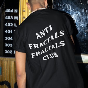 May include: A person wearing a black t-shirt with white text that reads "ANTI FRACTALS FRACTALS CLUB".