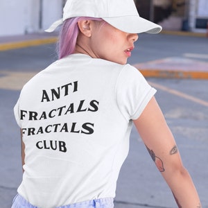 May include: A white t-shirt with black text that reads "ANTI FRACTALS FRACTALS CLUB". The person wearing the shirt has pink hair and is wearing a white baseball cap.