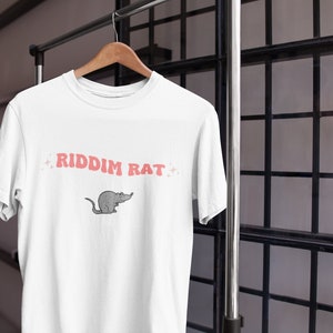 May include: White t-shirt with a pink graphic of a rat and the text "RIDDIM RAT" in pink letters.