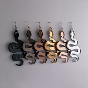 Può includere: Cinque paia di orecchini a forma di serpente in diverse finiture metalliche: nero, oro rosa, oro, argento e cromo.