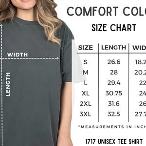 Peut inclure: Un t-shirt unisexe gris fonc&eacute; avec un tableau des tailles indiquant les mesures de longueur et de largeur en pouces. Le tableau comprend les tailles S &agrave; 3XL, avec une longueur allant de 67,6 cm &agrave; 82,6 cm et une largeur de 46,4 cm &agrave; 70,5 cm. Le texte "COMFORT COLORS" et "1717 UNISEX TEE SHIRT" sont &eacute;galement visibles.