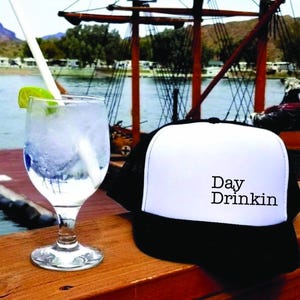 a hat sitting on top of a wooden table next to a drink
