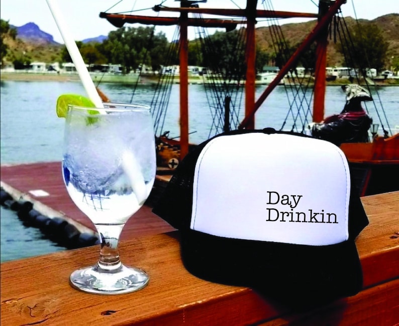 a hat sitting on top of a wooden table next to a drink