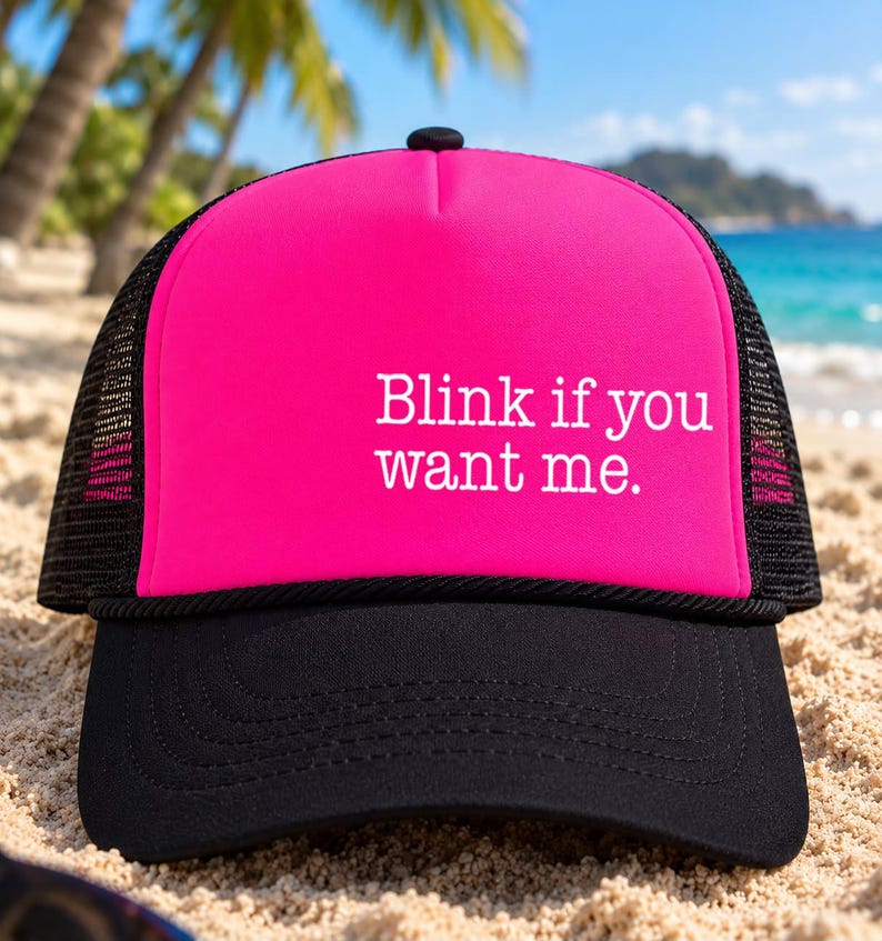 Puede incluir: Una gorra tipo trucker de color rosa brillante con visera negra y paneles traseros de malla negra. El panel frontal presenta el texto blanco "Blink if you want me.". La gorra tiene un frente de espuma estructurado y un bot&oacute;n negro.
