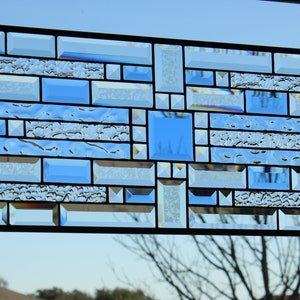 May include: A stained glass window with a geometric design featuring clear and blue glass pieces.
