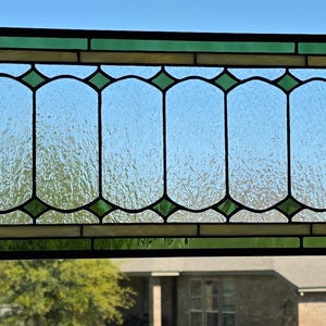 May include: A rectangular stained glass window panel featuring a series of vertical, textured clear glass panes framed by dark green glass borders. The design includes small green diamond-shaped accents at the top and bottom of each vertical section.