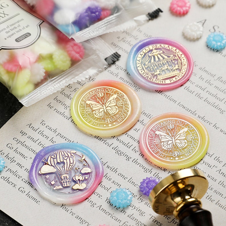 May include: Assortment of colorful wax seals with various designs, including a butterfly, a hot air balloon, and a circus tent. The seals are on a white background with text that reads "Breaking Out of the Cocoon" and "Starlight Playhouse".