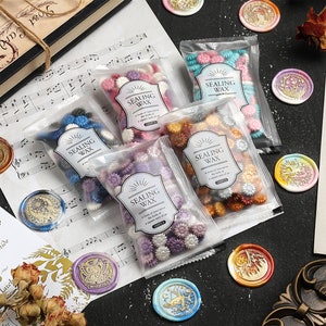 May include: Five clear plastic bags filled with colorful wax beads for sealing wax. Each bag has a label that says "Sealing Wax" and includes a description of the product. The bags are arranged on a sheet of music with several wax seals in various colors and designs.