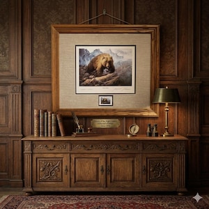 Puede incluir: Una impresión enmarcada de un oso pardo en un paisaje montañoso cuelga sobre un mueble de madera. El mueble presenta puertas y cajones tallados, con libros, una lámpara y otros objetos decorativos encima. La impresión está etiquetada como "Grizzly of the High Country - Collector's Edition - Circa 1970."