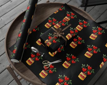 May include: Black wrapping paper with a repeating pattern of red heart-shaped plants in yellow pots. A wrapped gift with a brown ribbon, a roll of paper, scissors, and tape are on a wooden table.