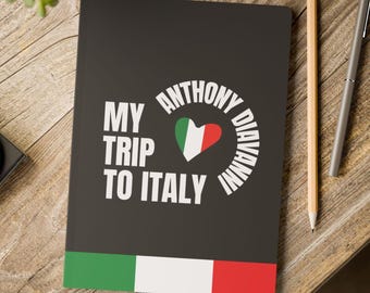 May include: A black notebook featuring the text "MY TRIP TO ITALY" and "ANTHONY DIAVANNI" in white. The design incorporates a heart in the colours of the Italian flag. The bottom edge has a green, white, and red stripe.