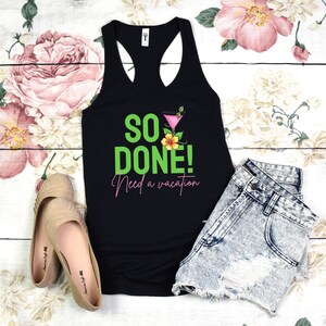 Pode incluir: Camisola de alças preta com o texto "So Done! Need a vacation" em letras verdes e cor-de-rosa. Também há uma flor rosa e um copo de cocktail na camisola.