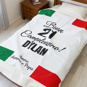 Könnte beinhalten: Weiße Decke mit grünen und roten Akzenten, die einer Flagge ähneln. Auf der Decke steht in schwarzer Schrift "Buon 21 Compleanno! DYLAN", sowie der Text "Amore, Mamma e Papa".