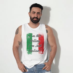 May include: White tank top with the text "I'm Not Yelling I'm Just Italian!" in black script. The text is framed by green and red brushstroke rectangles, resembling the Italian flag. The tank top is sleeveless.