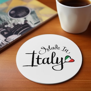 Op de afbeelding: Ronde witte onderzetter met de tekst "Made in Italy" in zwarte cursieve letters. Een klein rood, wit en groen hart met de kleuren van de Italiaanse vlag bevindt zich naast de tekst.