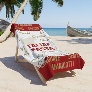 May include: A white and red beach towel with the words "Italian Pasta" in gold lettering. The towel features a variety of Italian pasta names, including lasagna, spaghetti, capellini, rotelli, and manicotti.