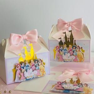May include: A set of three princess-themed party favor boxes with pink bows. Each box features a gold castle and a group of Disney princesses. The text on the boxes reads "Alexis turns 7".